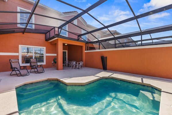 A swimming pool with a glass ceiling, lounge chairs, and a patio area.