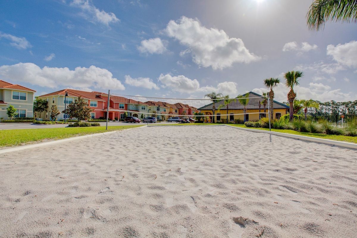 A sandy beach area with a row of colorful houses in the background.