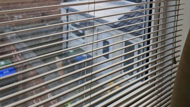 A window with horizontal blinds, a view of a parking lot, and a building in the background. - KELVIN HOUSE (Ferryhill)
