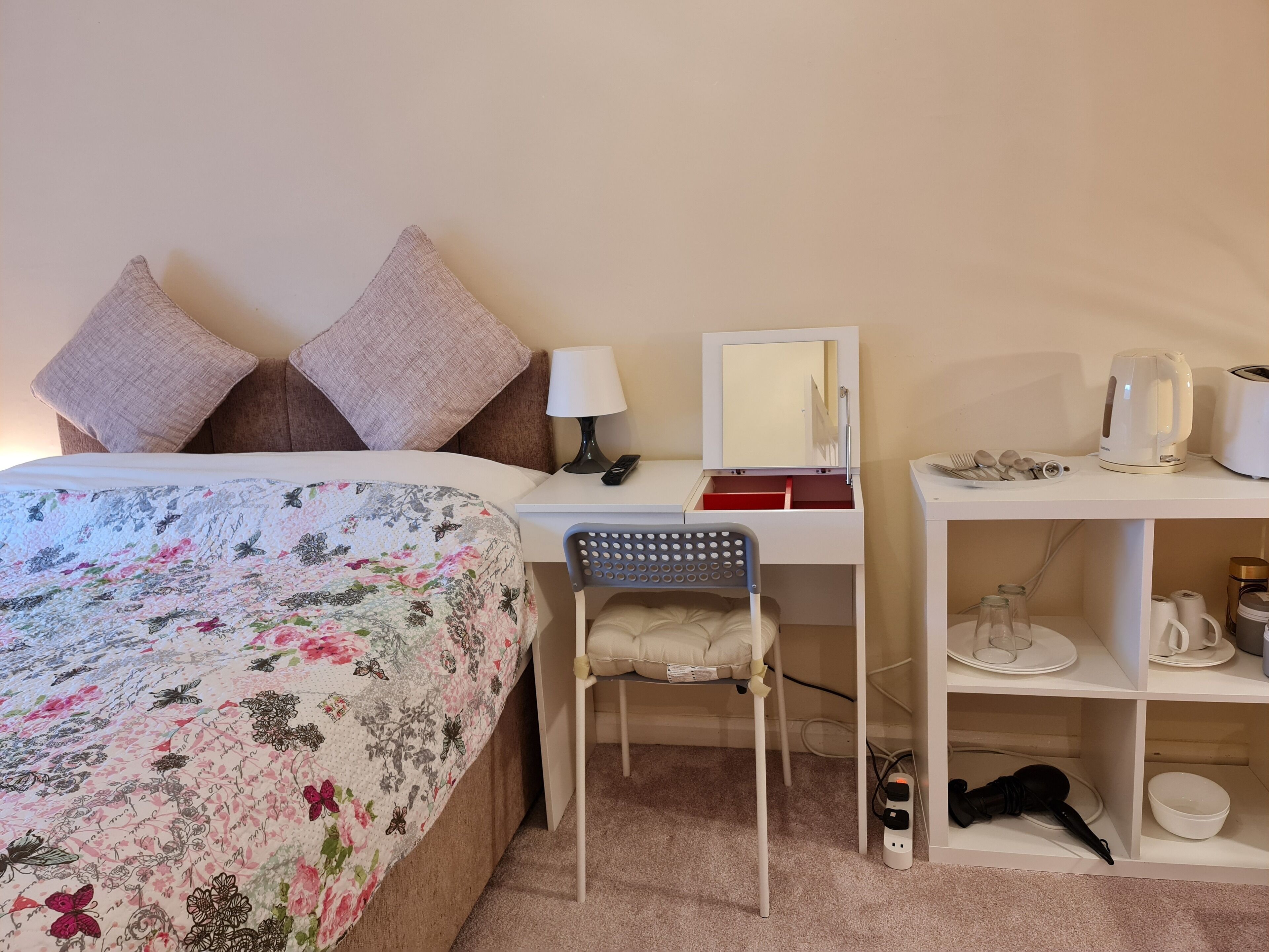Une chambre bien rangée, avec un lit, un bureau, une chaise, un miroir et une étagère contenant divers objets.