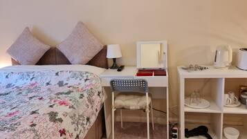 Une chambre bien rangée, avec un lit, un bureau, une chaise, un miroir et une étagère contenant divers objets.