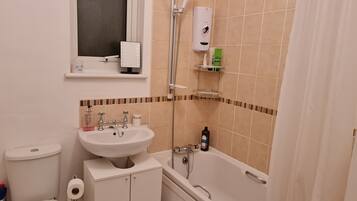 A bathroom with a toilet, sink, and bathtub. There are toiletries on the sink and a showerhead above the bathtub.