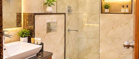 A modern bathroom with a marble vanity, a glass shower enclosure, and a toilet.