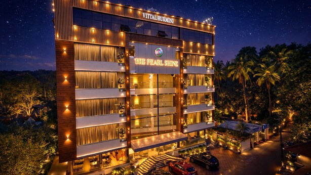 Un hôtel à plusieurs étages, reconnaissable la nuit grâce à une enseigne bien visible portant les noms « The Pearl Shine » et « Vittalurukmini ».