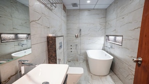 A modern bathroom with a large bathtub, a separate toilet, and a vanity with a mirror.