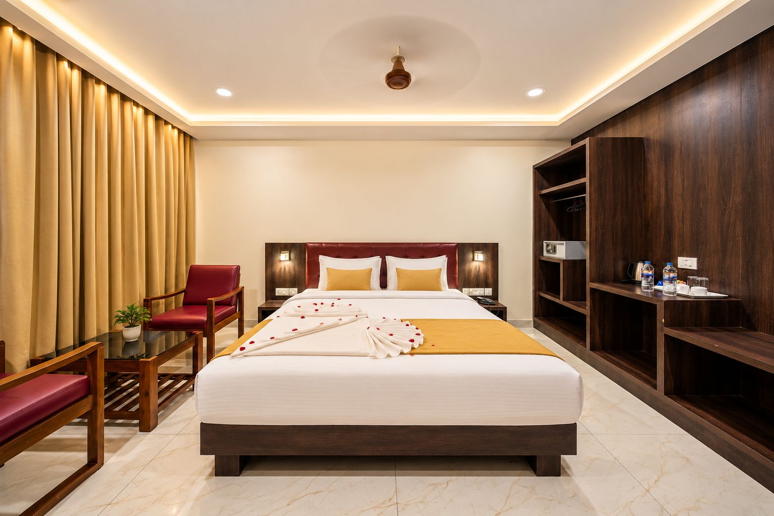 A hotel room with a large bed, a red chair, a small table, and a wooden wardrobe.