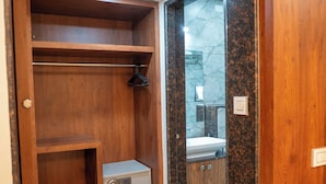 A wooden closet with shelves and a radio, a marble-tiled floor, and a view of a bathroom with a sink and mirror.