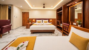 Une chambre d’hôtel avec un grand lit, une armoire en bois, un coin salon avec un fauteuil et une petite table agrémentée d’une plante.