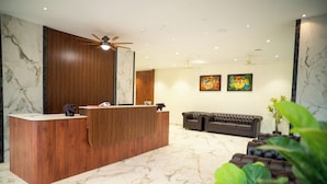 A reception area with a wooden reception desk, a tufted sofa, and a ceiling fan.