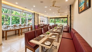 Un restaurant avec une longue table à manger, des banquettes rouges et des ventilateurs de plafond.