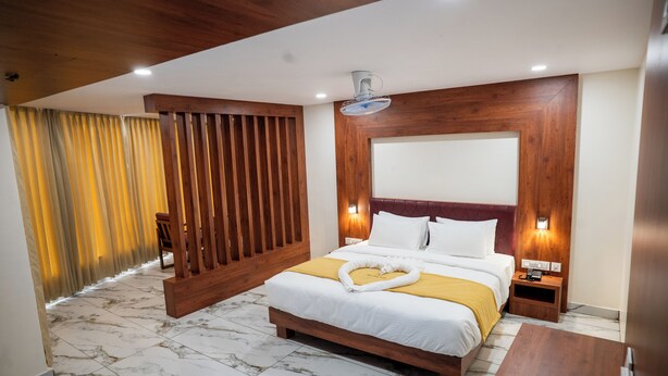 A hotel room with a wooden headboard, a bed with white linens, a wooden nightstand, and a marble floor.