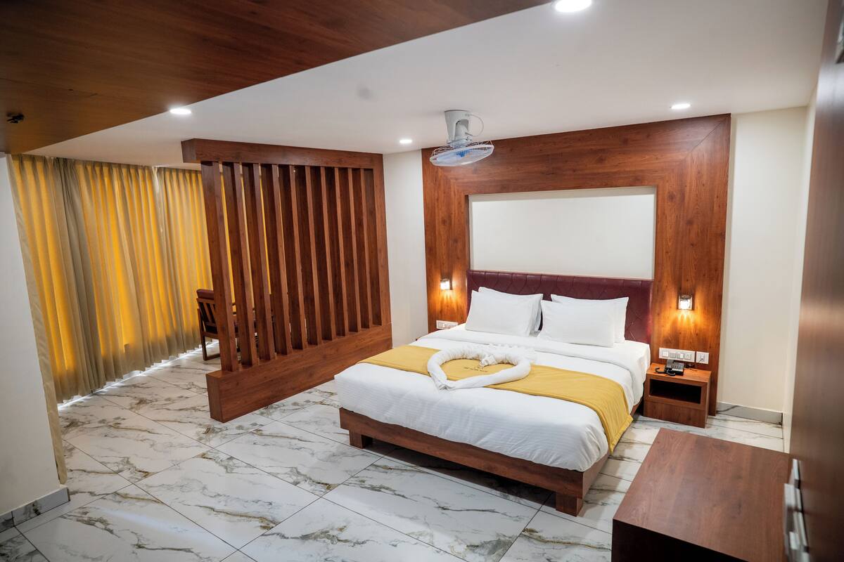 Ein Hotelzimmer mit einem hölzernen Kopfteil, einem Bett mit weißer Bettwäsche, einem Nachttisch aus Holz und einem Marmorboden.