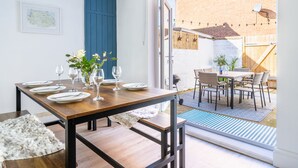 A dining area with a wooden table set for four, a white furry rug, and a view of the backyard through an open door. - 12 Hans Place, Cromer, Norfolk (Cromer)
