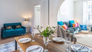 A modern living room with a dining table set for four, a teal sofa, and a striped armchair. - 12 Hans Place, Cromer, Norfolk (Cromer)
