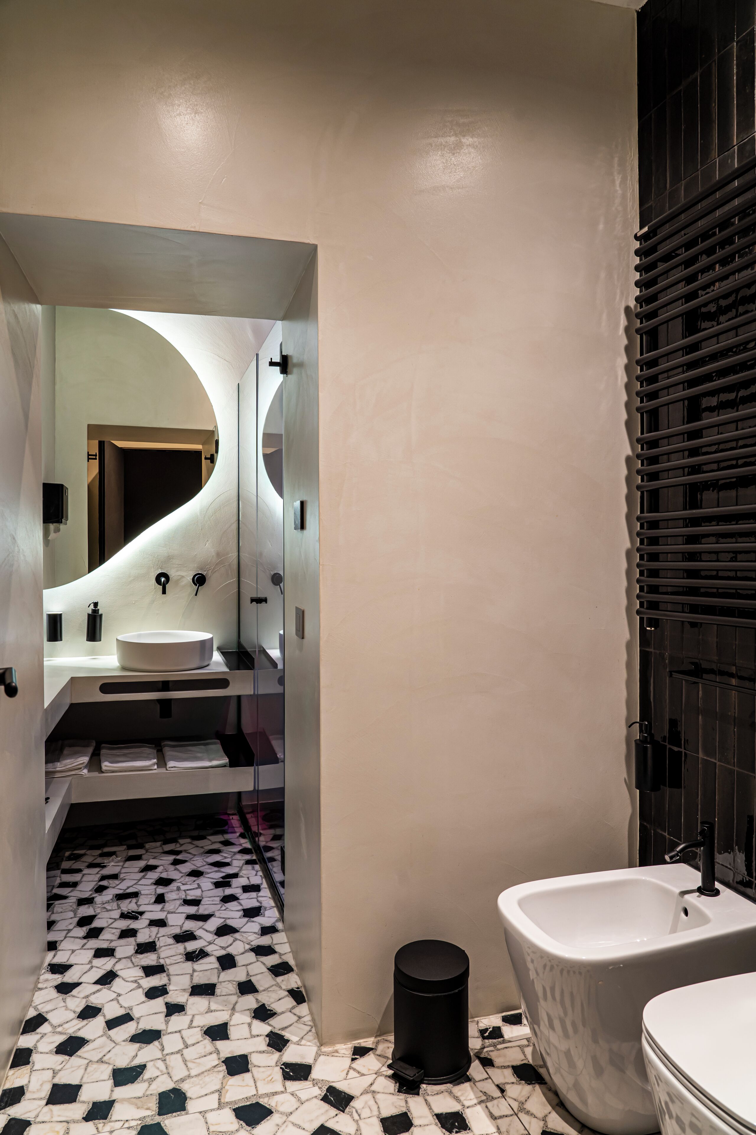 Un bagno moderno con un lavandino bianco, una vasca freestanding e un cestino nero.