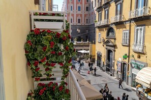 Una stretta via fiancheggiata da edifici, con balconi e alcuni passanti.