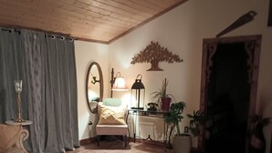 A cozy living room with a wooden ceiling, a round rug, a sofa, a table, and a lamp.