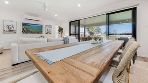 Un salon moderne avec une table à manger en bois, un canapé blanc et de grandes fenêtres.
