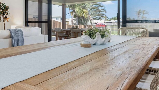 Une pièce spacieuse avec une table à manger en bois, un canapé blanc et des chaises en osier.
