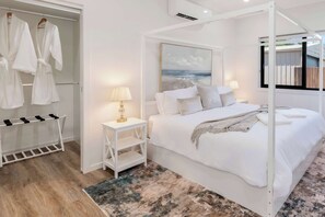 A bedroom with a bed, a nightstand, a lamp, a window, and a closet with robes. - Burnett Heads Beach Family Escape (Burnett Heads)