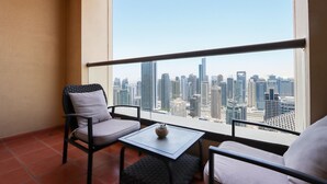 A balcony with two chairs and a small table, overlooking a cityscape with tall buildings.