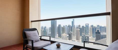 A balcony with two chairs and a small table, overlooking a cityscape with tall buildings.
