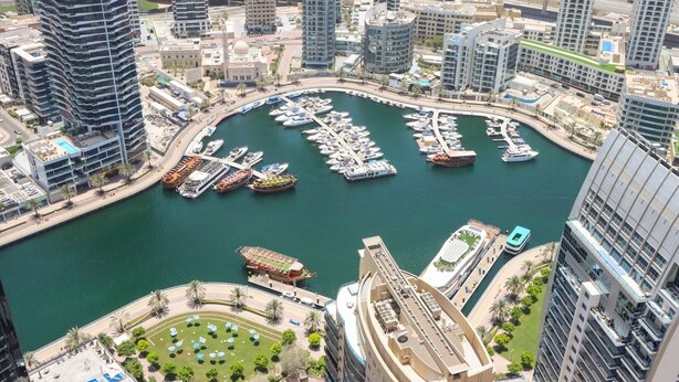A marina surrounded by high-rise buildings, with boats docked and a clear view of the water.