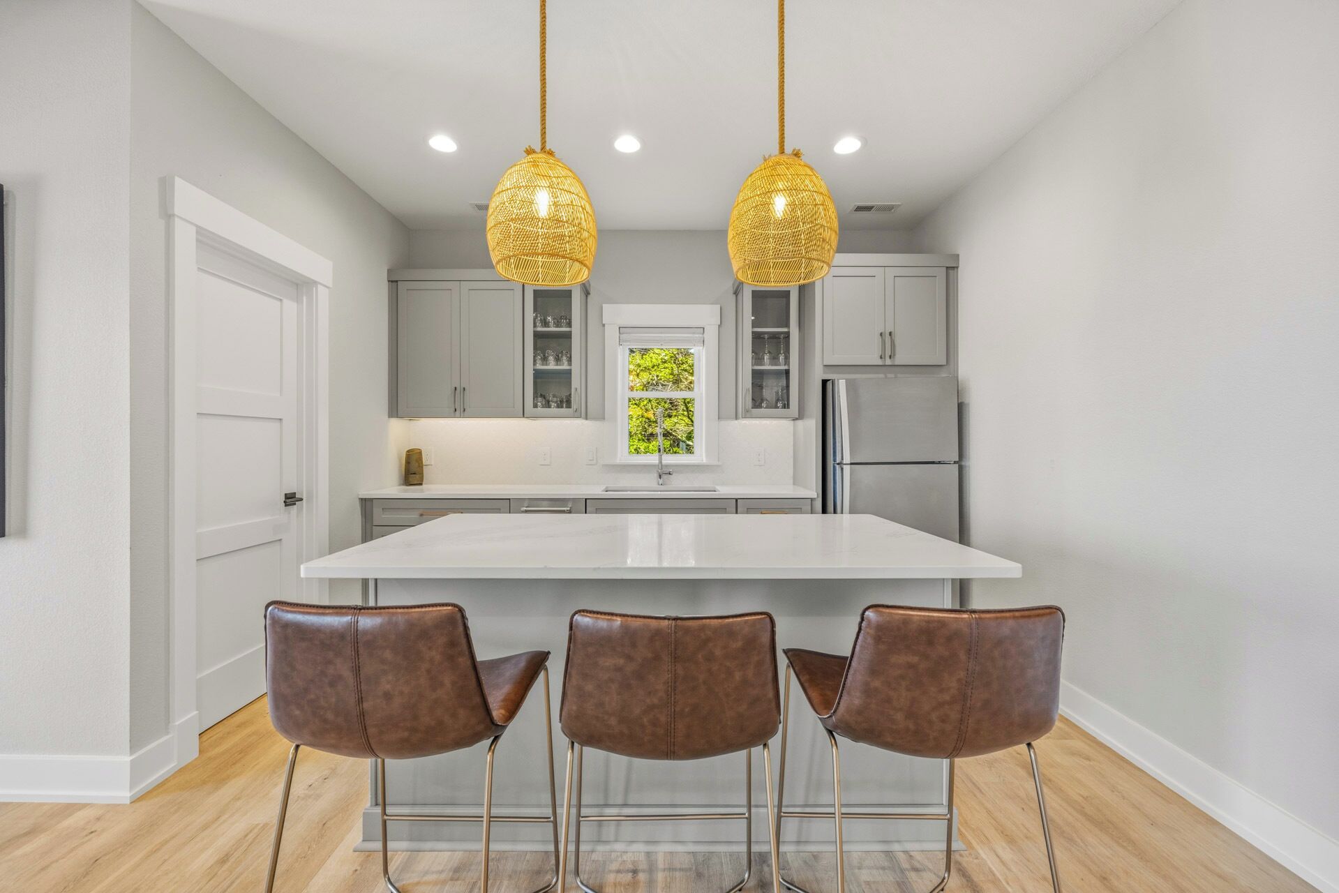 Une cuisine moderne dotée d’un îlot central, de luminaires suspendus et de tabourets de bar.