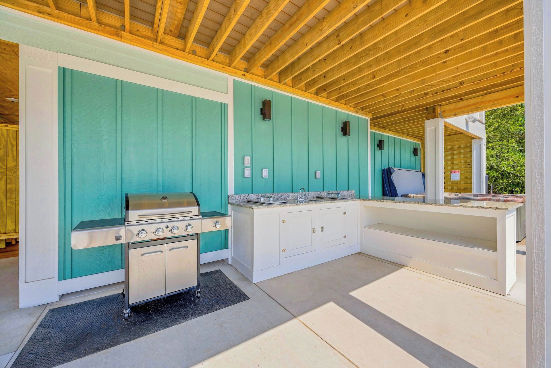 A kitchen with a built-in grill, white cabinets, and a teal wall.