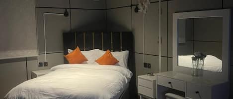 Un dormitorio moderno con una cama grande, una mesita de noche, un aparador y un tocador.