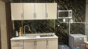 A compact kitchen with a microwave, stove, and refrigerator. - welcome apartment (Jeddah)