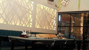 A restaurant interior with a booth seating area, a bar counter, and decorative hanging plants. - Hr Residency (Mumbai)