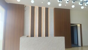 A reception area with a modern design, featuring a reception desk, vertical wooden panels, and a ceiling with spherical light fixtures. - Hr Residency (Mumbai)
