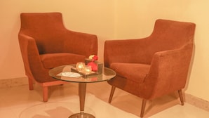 Two armchairs and a glass coffee table with a tray of items. - Hr Residency (Mumbai)