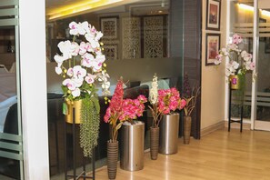 A reception area with vases of orchids and a reception desk. - Hr Residency (Mumbai)