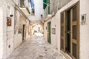 Une ruelle étroite, pavée de pierres, avec une enseigne indiquant « Suite 31 » et une grande fenêtre ornée d’une grille métallique.