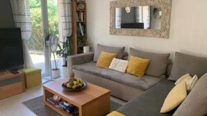 A living room with a sofa, a coffee table with a fruit bowl, a bookshelf, and a TV. - French Riviera Villa (Biot)