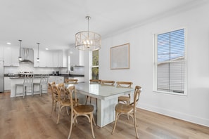 Una cocina moderna con armarios blancos, una mesa de comedor de vidrio y sillas de madera.