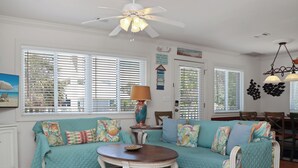 Un salon chaleureux avec un canapé de couleur turquoise, une table basse en bois et un ventilateur de plafond.