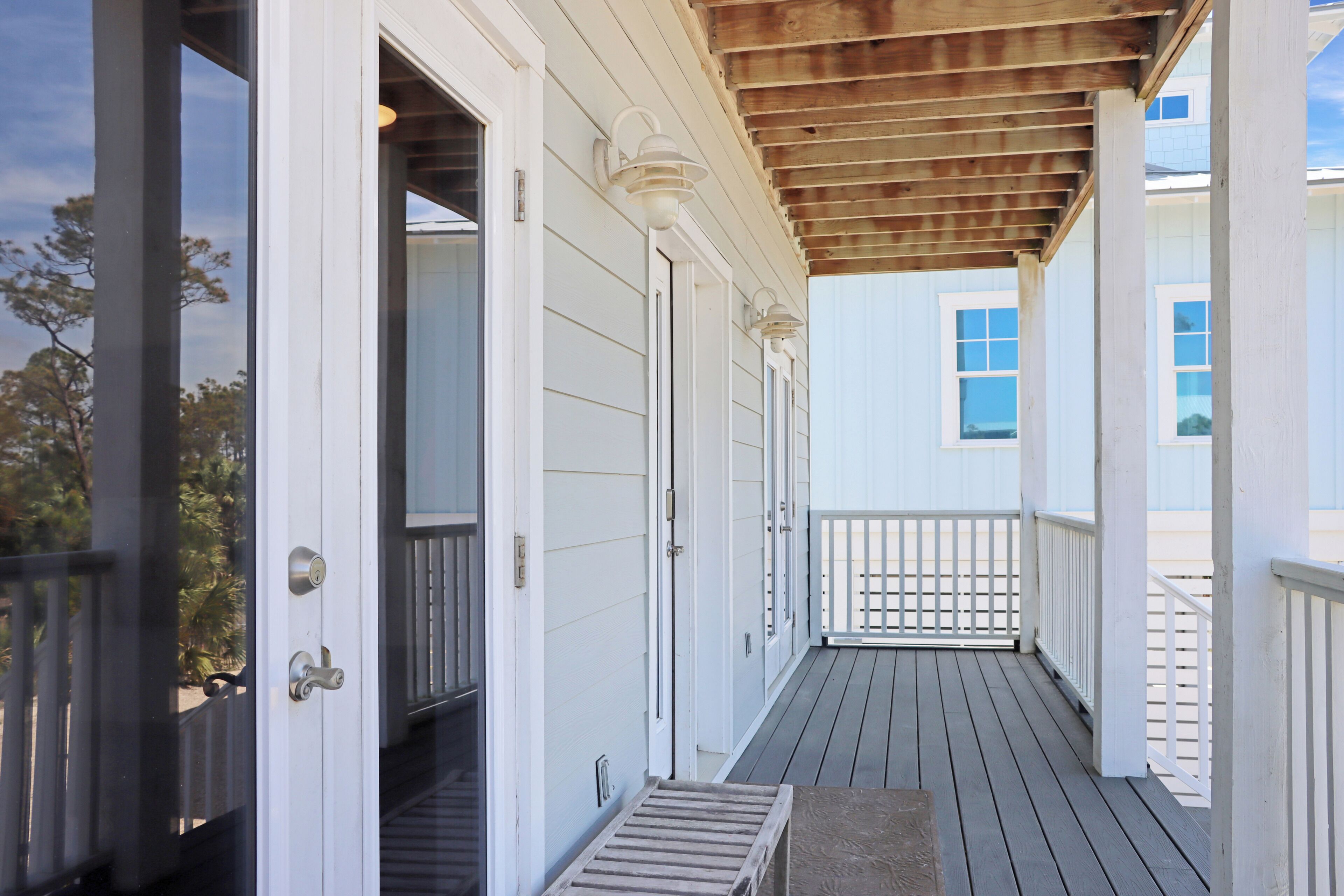 A covered porch with white railings and a wooden ceiling.
