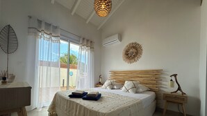 Une chambre à coucher comprenant un lit, une table de chevet, une lampe, un climatiseur fixé au mur et donnant sur l’extérieur.