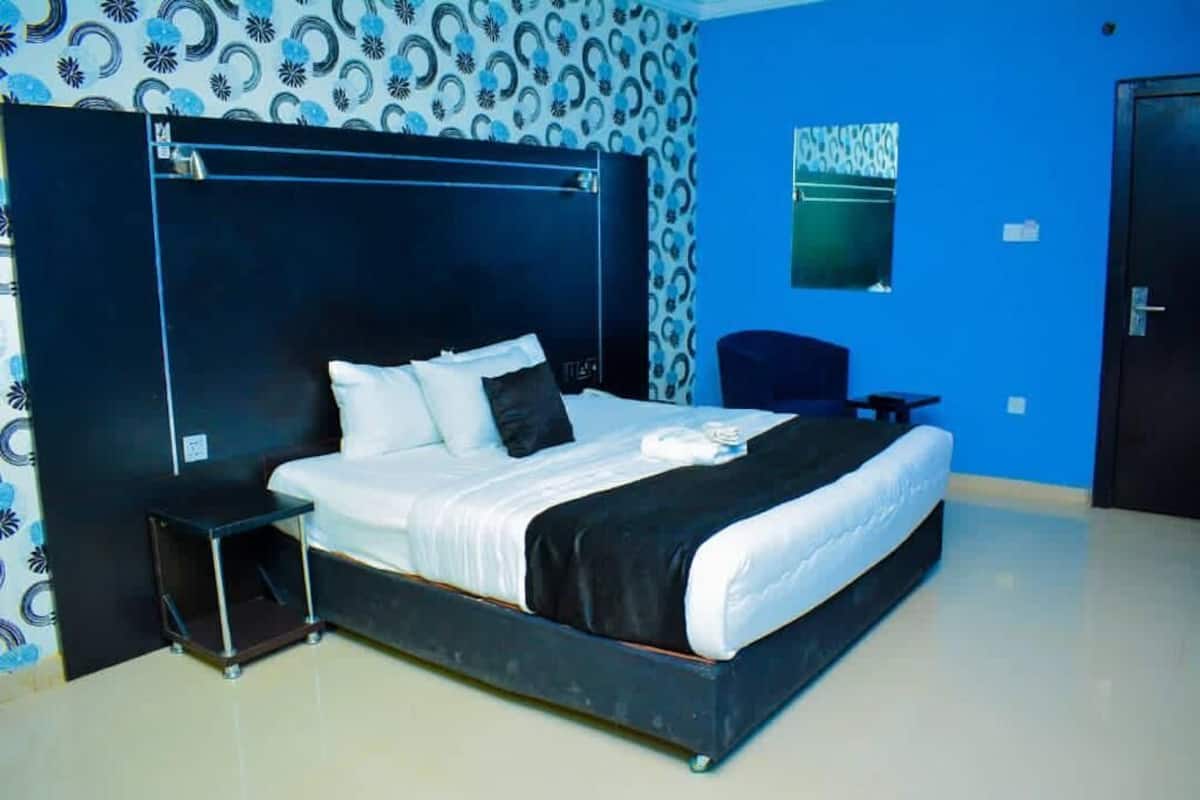 A bedroom with a large bed, a bedside table, and a chair.