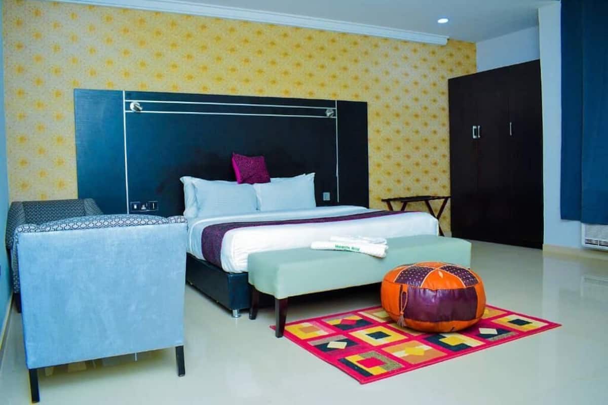 A bedroom with a bed, a bench, a colorful rug, and a large orange bean bag.