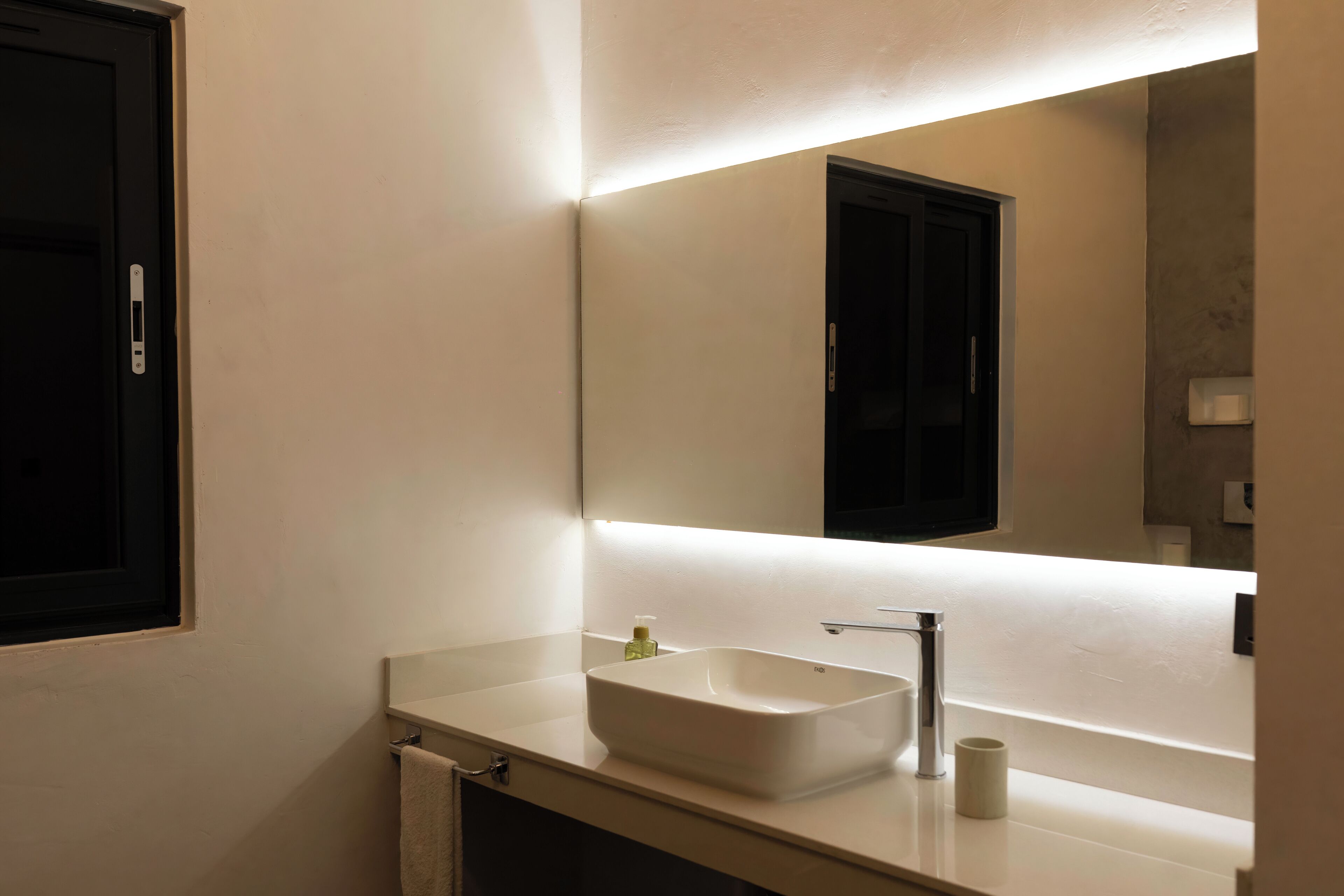 A modern bathroom with a white sink, a mirror, and a towel rack.