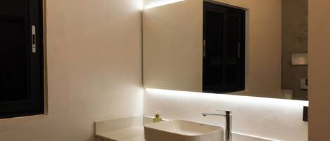A modern bathroom with a white sink, a mirror, and a towel rack.