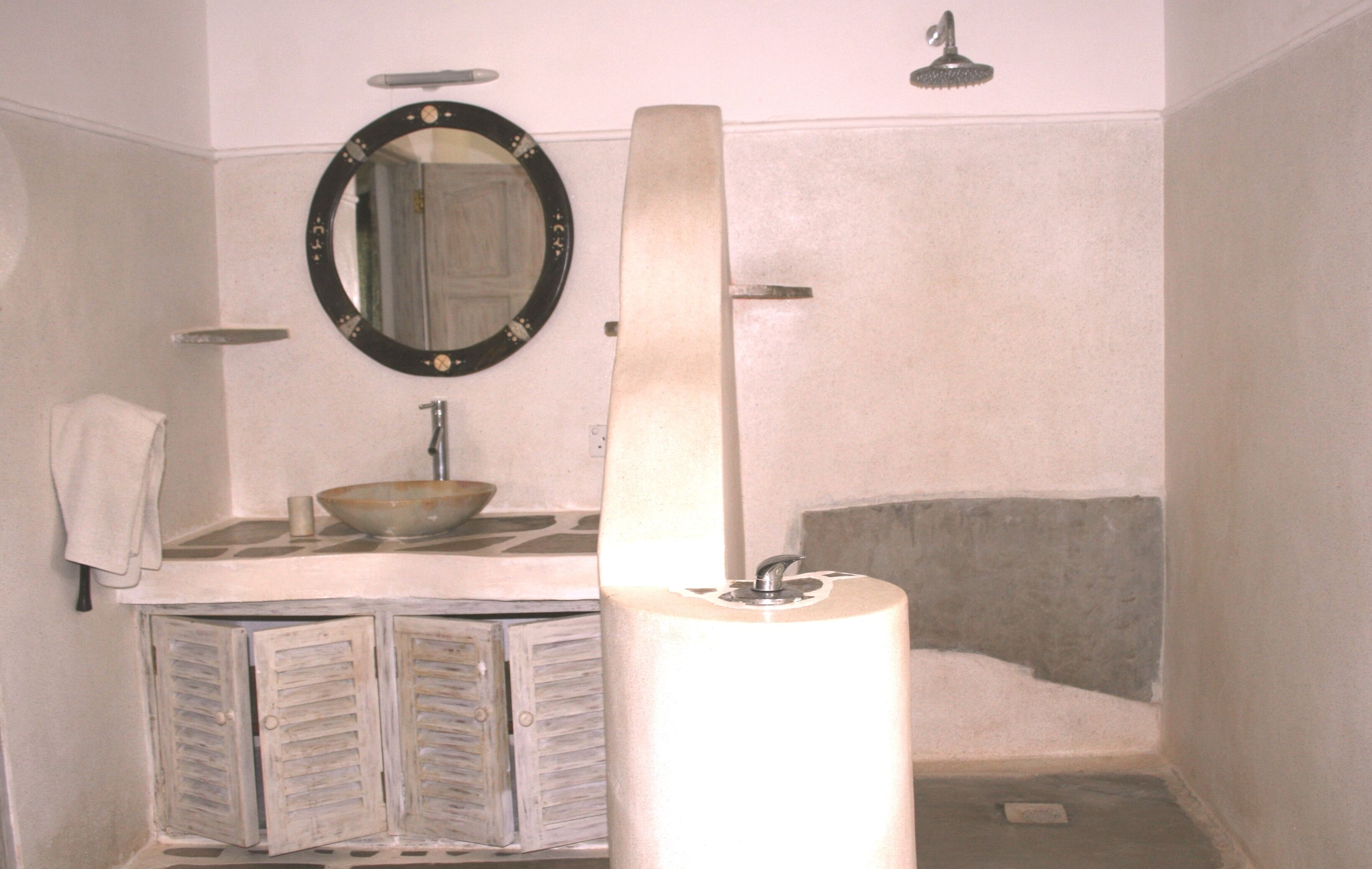 Een badkamer met een wastafel, spiegel en douche.
