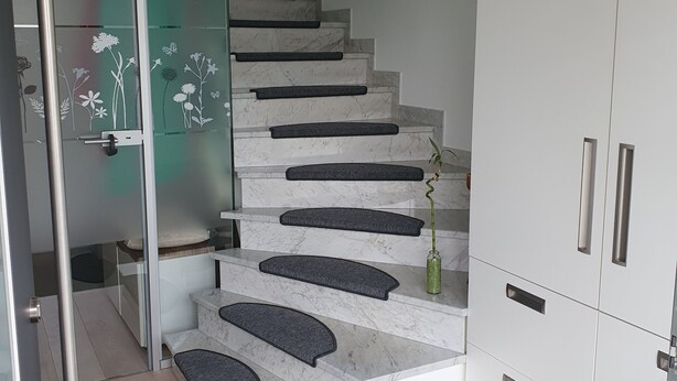 A modern staircase with a glass door leading to a room with white cabinets and a black rug. - "Modern 2-room apartment in Troisdorf, centrally located - perfect retreat!" (Troisdorf)