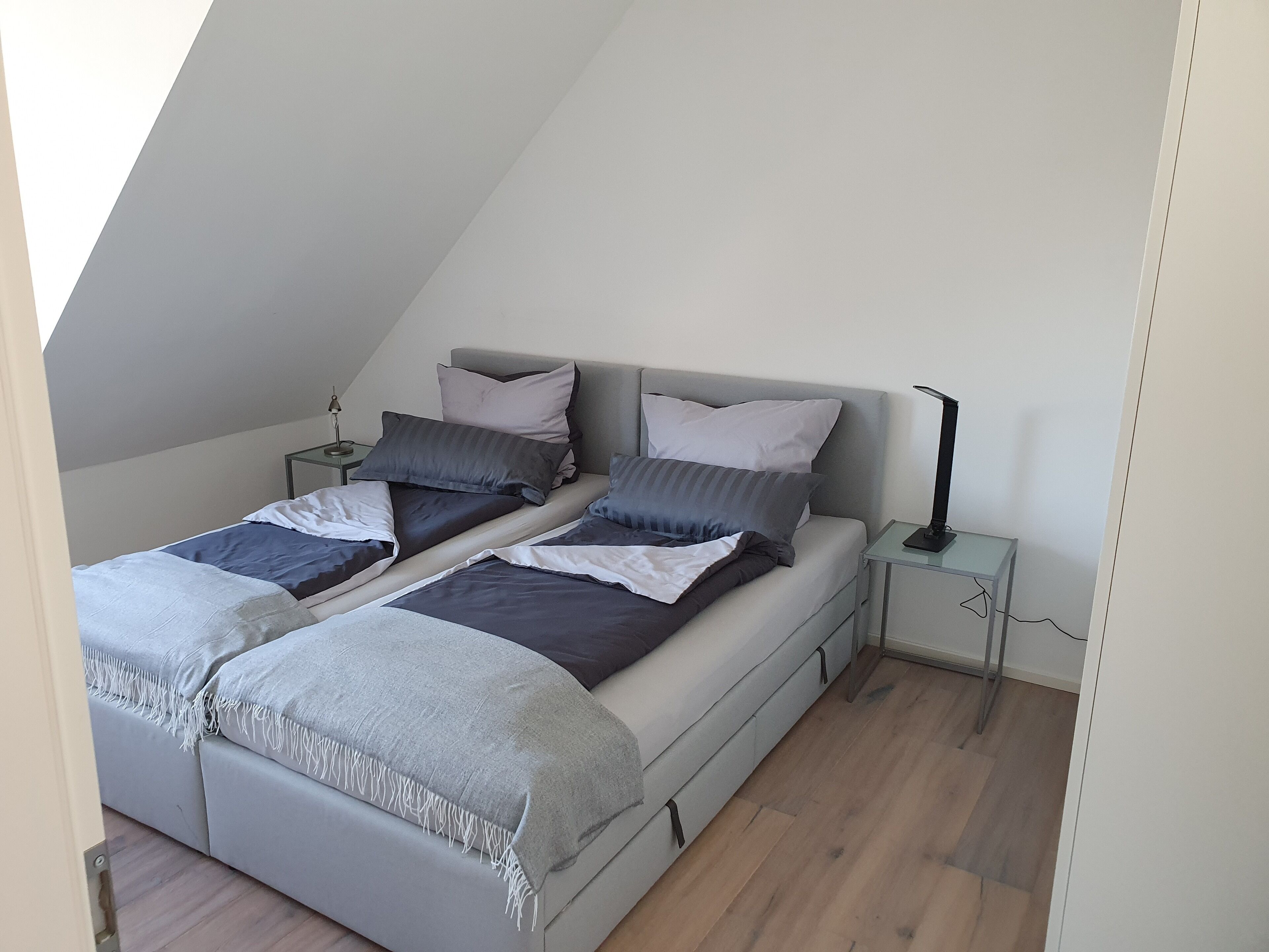 A bedroom with two beds, a nightstand, and a lamp.