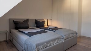 A modern bedroom with a loft-style bed, a bedside table, and a nightstand. - "Modern 2-room apartment in Troisdorf, centrally located - perfect retreat!" (Troisdorf)