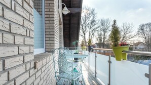 A balcony with a metal table and chairs, a potted plant, and a view of the surrounding area. - "Modern 2-room apartment in Troisdorf, centrally located - perfect retreat!" (Troisdorf)